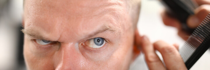 Portrait of a pensive man who is being cut with a machine. Haircut at home concept