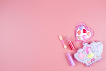 Cosmetics for little girls, baby lipstick, eye shadow, lip gloss, on a pink background.