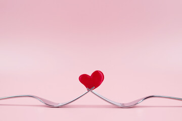 Red Heart between two forks, on a pink background. Valentines day concept