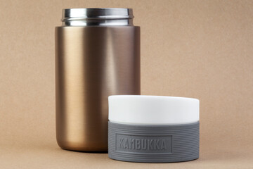 Freelancer workplace at laptop, stylish coffee drinks from thermos and takes notes.