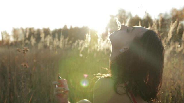 girl sprinkles perfume, nature .Beautiful fashion woman spraying perfume on her neck