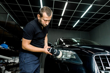Car detailing and polishing concept. Close up of male worker with orbital polisher, polishing...