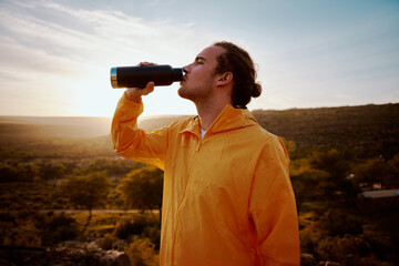 Portrait of young man drinking water from bottle while resting after run