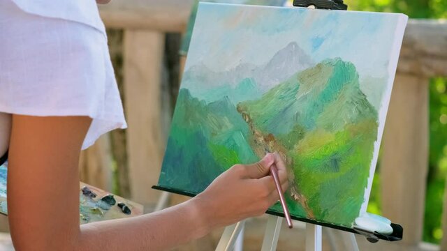 Female painter is creating a picture with mountain canyon