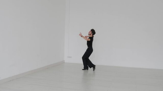 Young handsome man dancing ballroom dancing. A professional ballroom dancer trains in a large white hall.