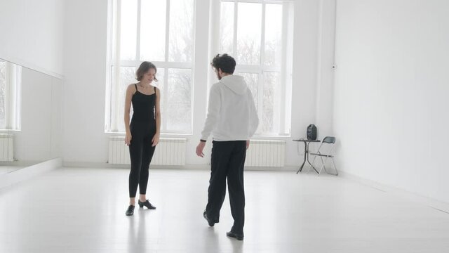 Young beautiful couple studying ballroom dance. A professional ballroom dancing couple dances in a large, bright, white hall