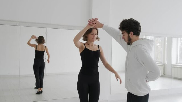 Young beautiful couple studying ballroom dance. A professional ballroom dancing couple dances in a large, bright, white hall