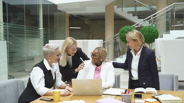 Portrait of open-minded friendly women laughing, multi-ethnic team of females enjoy coworking. Business people concept.