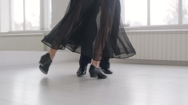 Young beautiful couple studying ballroom dance. A professional ballroom dancing couple dances in a large, bright, white hall