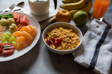 Cornflakes with cherry in a bowl along with food ingredients