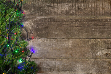 Branches of a Christmas tree with a festive garland as a frame on a rustic background. Top view,...