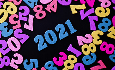 Happy New year 2021. Wooden numbers 2021 on black background surrounded with colorful numbers. New year concept. Flat lay. Close up of 2021