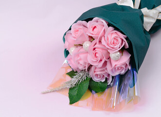 Bouquet of flowers in a paper vase, pink background. Artificial flowers