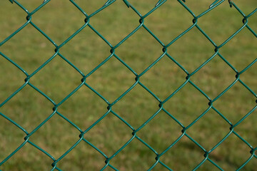 view through green chain link fence onto a green area in the background