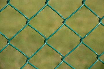 view through green chain link fence onto a green area in the background