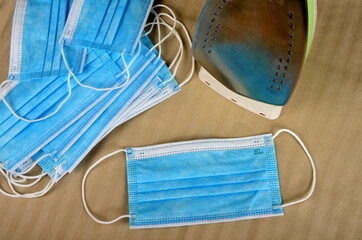 House electric iron and blue face masks. Protection and Prevention from covid19, Coronavirus concept.