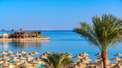 Relaxing at paradise beach - Chaise lounge and parasols - travel destination Hurghada, Egypt - obrazy, fototapety, plakaty