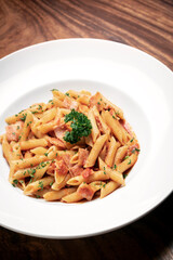 penne amatriciana tomato and ham sauce pasta on wood table