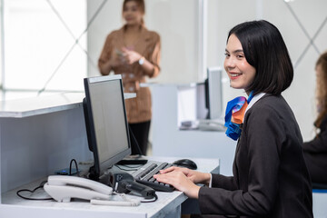 Woman in check in counter taking passport for verification from passenger man. Happy smiling hostess at check in working with her colleague. Business trip in the airport. Good service mind.