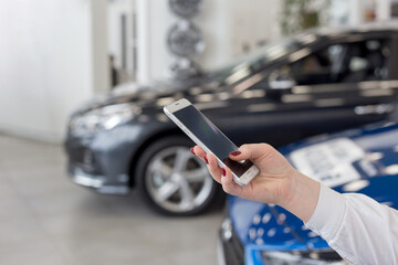 Saleswoman using mobile smart phone at dealer showroom. Modern working process.