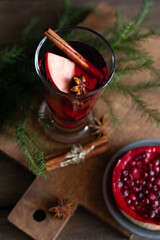 A glass of christmas mulled wine with spice and a berry pie