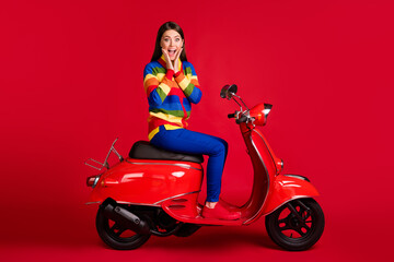 Fototapeta na wymiar Portrait of charming cheerful amazed girl sitting on moped having fun great sale isolated over bright red color background