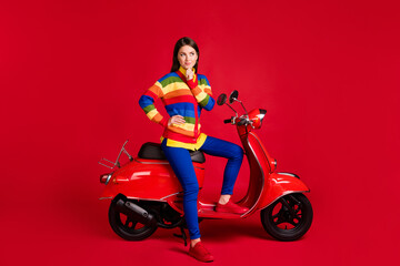 Fototapeta na wymiar Photo portrait of minded woman touching face chin with finger sitting on scooter isolated on vivid red colored background