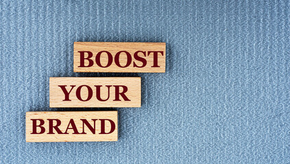 BOOST YOUR BRAND - words on wooden bars on a gray background with a free space.