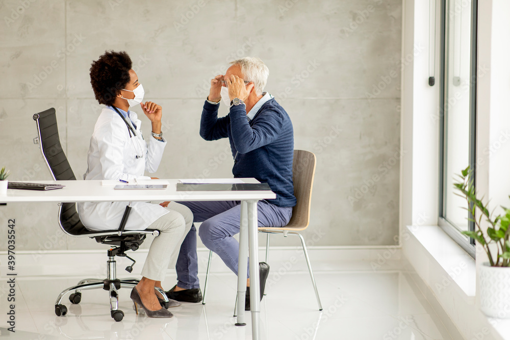 Wall mural senior man with protective facial mask receive news from black female doctor