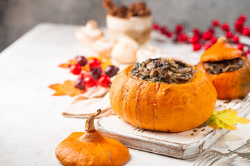 Tasty autumn stuffed pumpkin with fresh mushrooms, spinach and vegetables ready on rustic white table