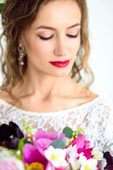 joyful girl bride in a white knitted dress posing with a bouquet of flowers