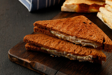 Toasted rye sandwich with ham cut into halves on table