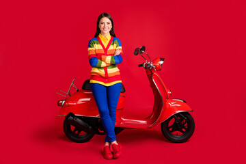 Obraz na płótnie Canvas Photo portrait of woman with folded arms sitting on retro scooter isolated on vivid red colored background