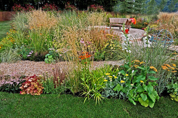 A gravel garden with seating and a selection of grasses, flowers and plants