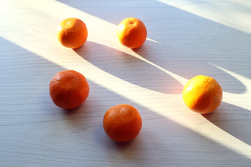 Ripe tangerines on a light background in the sun and shadows from objects, side view