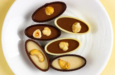 White saucer on a yellow background with chocolates. View from above