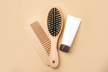 Wooden combs and a bottle for cream on a beige background, place for text. Hair Care Cosmetics