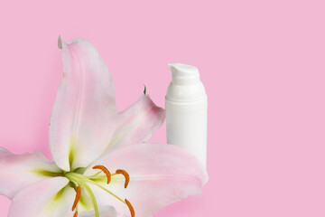 Natural organic spa cosmetic product in white bottle, lily flower on pink background. The concept of krasrty and rest with space for text.