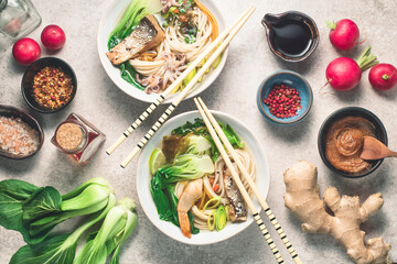 Hot Udon noodles with seafood and fish or noodles soup based on Dashi broth with vegetables, spicy and dressing  on the gray stone background, flat lay. Asian food concept