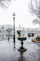 Fototapeta premium Basel, Basiliskbrunnen, Basilisk, Brunnen, Rhein, Rheinufer, Kleinbasel, Altstadt, Stadt, Martinskirche, Rheinbrücke, Winter, Schnee, Schneedecke, Strassenlaterne, Parkbank, Basel-Stadt, Schweiz