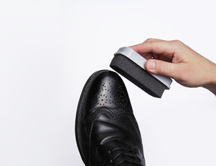 men's hand with a sponge for polishing shoes polishes leather shoes on the white background. isolate