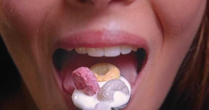 Young woman mouth eating yogurt with colorful hoops cereal
