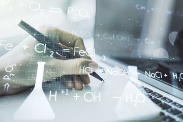 Double exposure of creative chemistry concept with hand writing in notebook on background with laptop, research and development concept