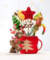 Christmas gingerbread, candy on sticks and teddy bear. Christmas festive card with garland lights and decorations.