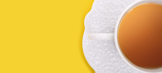 Obraz premium Porcelain cup with tea on yellow background