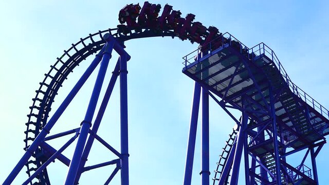 People in multiple cars ride on roller coaster in amusement park sky background