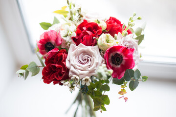 Fresh anemones and roses flowers on window background. Close up of bouquet with el toro roses, latin pompon roses, white matthiola and eucalyptus