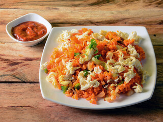 Tasty Schezwan Egg fried rice with tomato sauce served in white plate over a rustic wooden background, Indian cuisine, selective focus