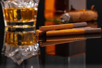 Glass of whisky and cigar on black background