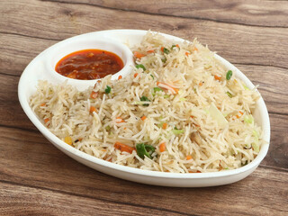 Healthy and tasty veg fried rice made of mixed veggies served in bowl over a rustic wooden background, Indo chinese, Indian cuisine, selective focus